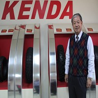 楊董事長站在KENDA標誌和輪胎的前面
