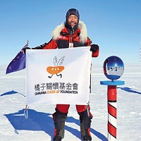 劉柏園好不容易抵達南極點，拿著橘子關懷基金會的旗幟合照。（遊戲橘子提供）